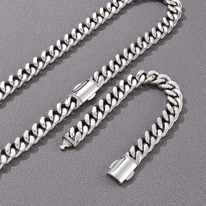 Close-up of silver Cuban link necklace and bracelet set with box clasp on grey background