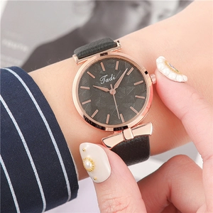 Close-up of a women's rose gold watch with leaf pattern dial and leather strap