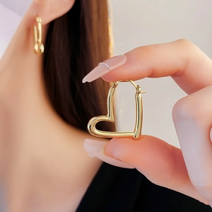 Détail des boucles d'oreilles créoles dorées en forme de cœur avec finition polie