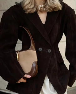 Détail du revers de veste en daim et sac porté épaule en cuir marron à boucle dorée