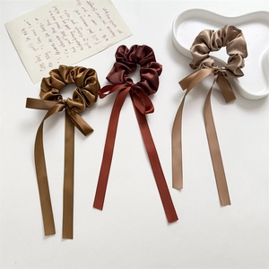 Detail of satin scrunchies with long ribbons in brown, burgundy, and champagne colors
