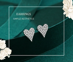 Macro shot of silver heart studs with pavé diamonds on a green velvet ribbon
