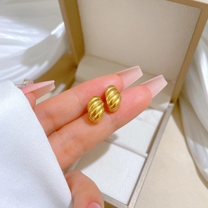 Detailed close-up showing the size and texture of a gold-colored croissant stud earring