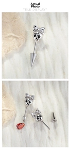 Detail of punk style skull and bow earring with vibrant red crystal droplet pendant