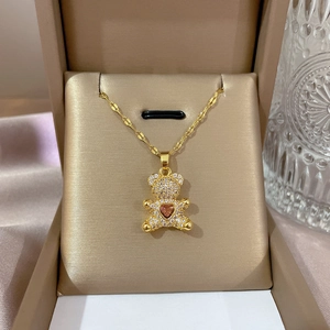 Detail of bear pendant with pink heart gemstone and zircon inlay in a gold jewelry box