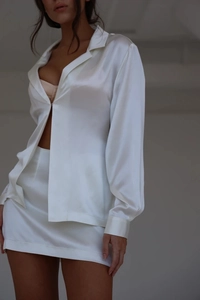 Detailed view of women's white satin long sleeve shirt and matching mini skirt set