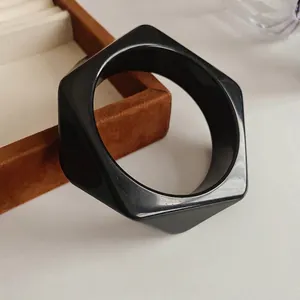Minimalist black hexagonal bangle with a high-gloss finish and avant-garde round edges