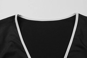 Detail of V-neckline with white contrast piping on a black long sleeve shirt