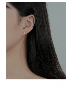 Close-up of S925 silver gold-plated rhombus earrings with three white zircon stones