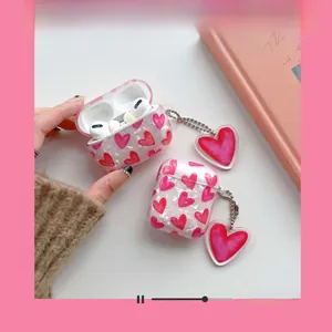 Detail of pearlescent white AirPods case with pink heart patterns and metal chain pendant