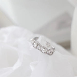 Macro detail of silver wave open ring with faux pearls and sparkling diamond accents