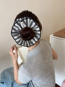 Detail of a large black and white striped fabric scrunchie in a high bun hairstyle