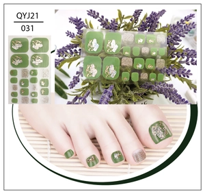 Close-up of green toenail stickers with gold foil and shell fragments on feet