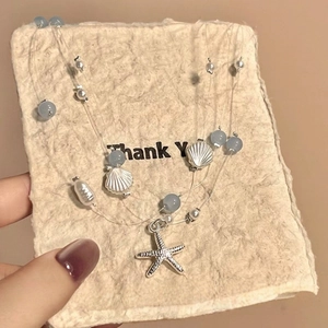 Detailed close-up of seaside style necklace with conch, starfish and pearl charms