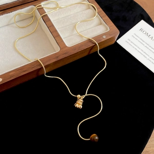 Detail view of golden snake chain necklace with tiger eye stone and diamond lucky bag pendant