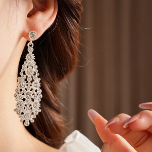 Primer plano de elegantes pendientes largos de plata en forma de rombo en una modelo