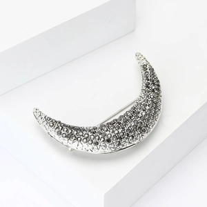 Silver crescent moon brooch with dark crystal pavé on minimalist geometric background