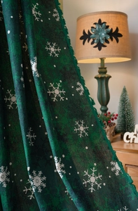 Detail of dark green Christmas curtain fabric with white snowflakes and fringe edge