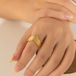Close-up of a gold V-shaped textured ring worn by a model with a vintage aesthetic