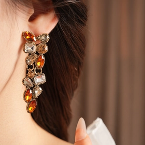 Detailed close-up of vintage drop earrings with amber crystals and gold finish