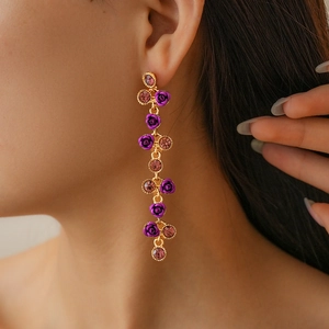 Vue détaillée de longues boucles d'oreilles dorées à glands avec roses et strass violets