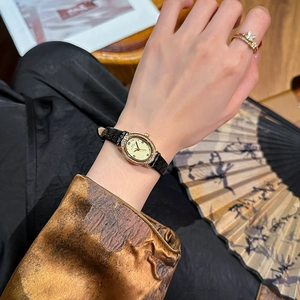 Elegant oval diamond gold watch with black leather strap on a model wrist