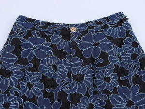 Close-up of black lace and denim shorts with floral embroidery and golden button