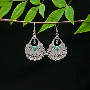 Detailed view of silver ethnic drop earrings with green enamel and beaded tassels