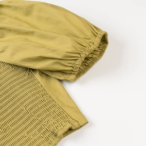 Detail view of mustard yellow smocked top with elastic cuffs and lantern sleeve design