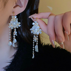 Détail de boucles d'oreilles fleurs avec longues pampilles en perles et pendentifs