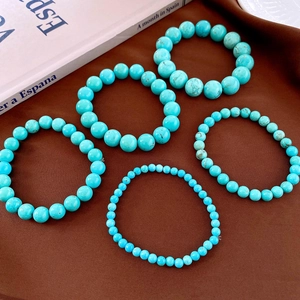 Detail of five turquoise bead bracelets with black mineral veins on dark fabric