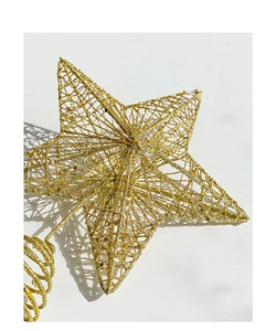 Close-up of golden glittery hollow star tree topper with metal mesh and spiral base