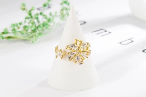 Detail of a rotating gold windmill flower ring with sparkling zircon and star accents