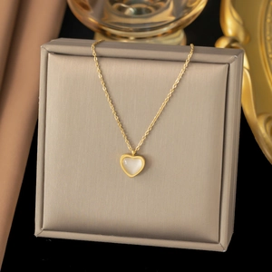 Gold layered heart pendant necklace with shell inlay displayed on a beige jewelry box