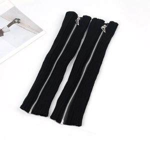 Black knitted leg warmers with silver zippers and triangle charms on a white background