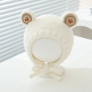 Détail du bonnet en peluche blanc pour bébé avec broderie cerise et protège-oreilles