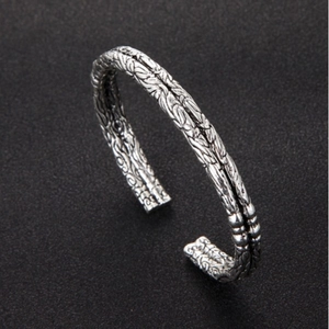 Retro silver open bracelet for men with intricate woven metal texture on dark background