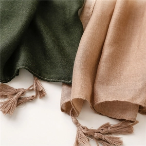 Detail of soft green and beige scarfs with fringe tassels and premium woven texture