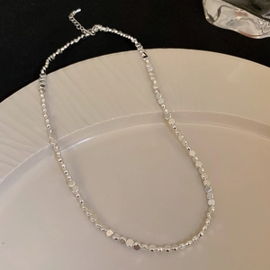Detail shot of silver nugget bead necklace with lobster clasp on ceramic plate