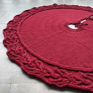 Detailed knit pattern on dark red Christmas tree skirt with decorative cable stitch texture