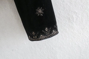Détail de la broderie florale dorée et des sequins sur le revers en velours de soie noir