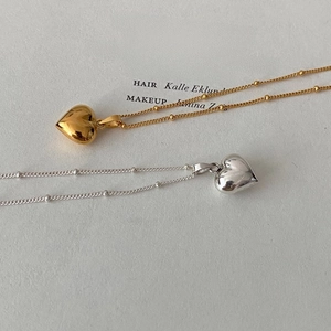 Close-up of heart pendants on beaded chains in gold and silver mirror finish