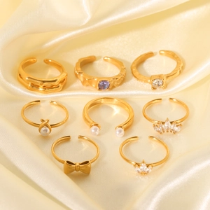 Detail view of 8-piece gold bow pearl rings set with zircon accents on yellow satin