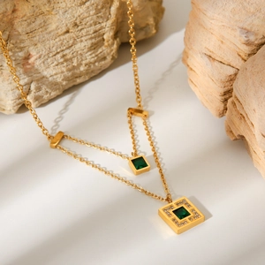 Detail of gold double-layer necklace with emerald green square pendants and zircon accents