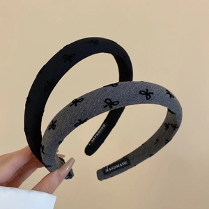 Detailed view of handmade sponge headbands with embroidered bows in black and gray