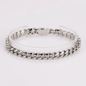 Polished silver stainless steel Cuban link bracelet displayed on a clear acrylic stand