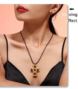 Wearing effect of golden hammered cross pendant with black gemstone on a cord necklace