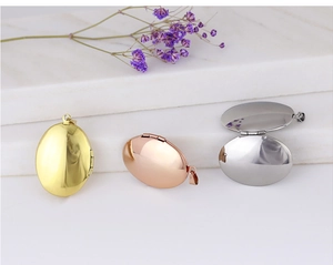 Three oval locket pendants in gold, rose gold, and silver on white marble background