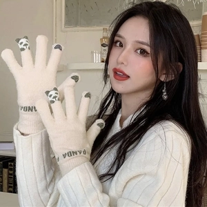 Detail view of cream-colored knit gloves with green panda pattern and panda text on cuffs