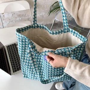 Detail view of the interior compartment and blue plaid woven fabric of this large tote bag